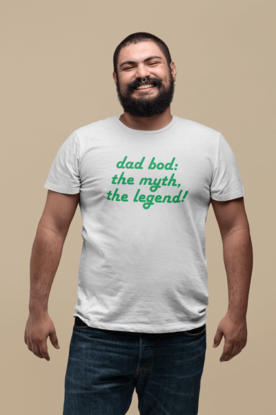 Man wearing a white shirt with "dad bod: the myth, the legend!" text, celebrating dad bod humor and style.