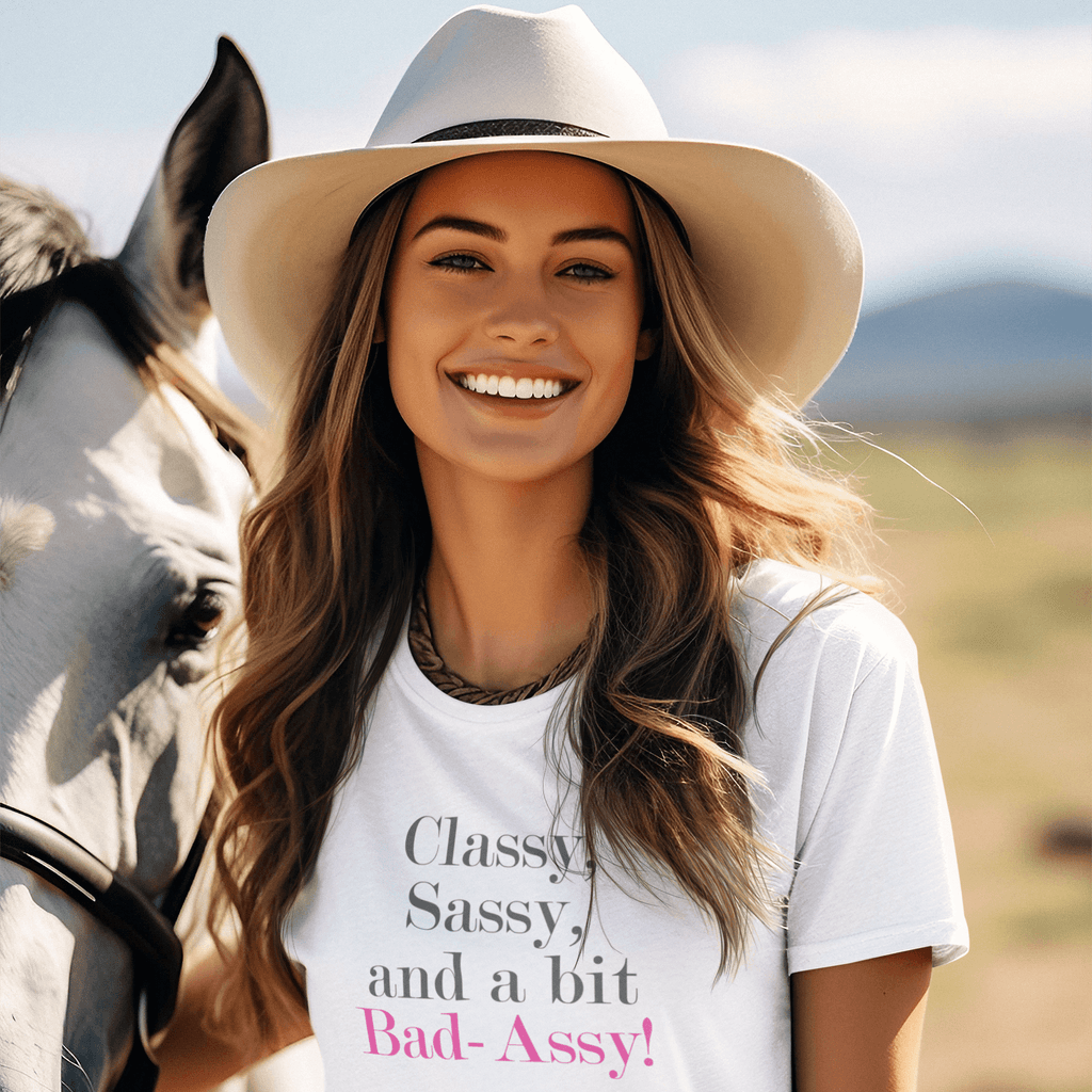 Woman in hat wearing "Classy, Sassy, and a bit Bad-Assy" premium women's tee, smiling next to a horse outdoors